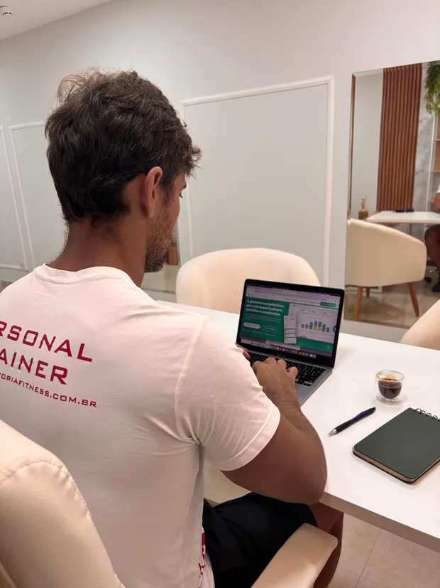 Dr. Victor Curty montando o planejamento de treino de uma aluna no computador